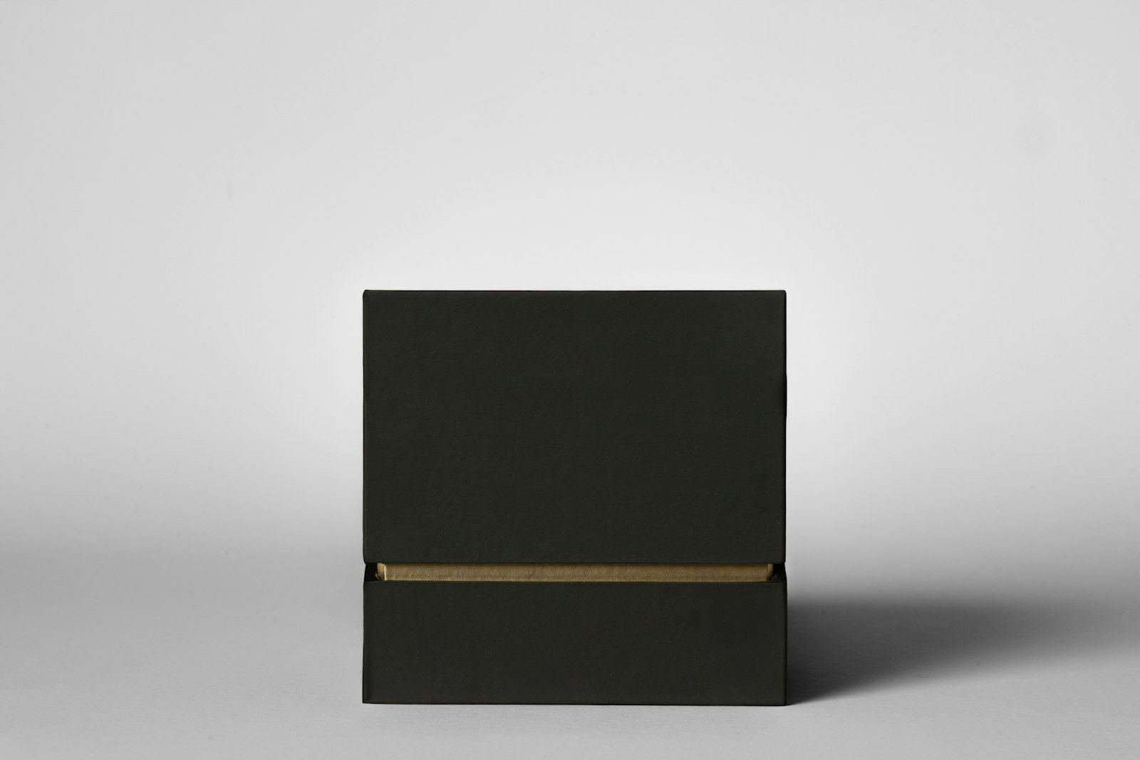 Caja negra de regalo con detalle dorado sobre fondo claro